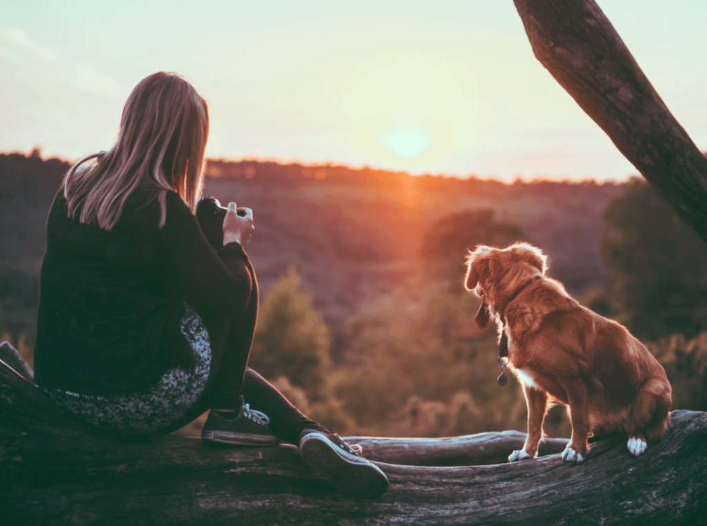 Lady sitting in a jungle with her dog